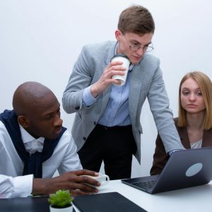 A diverse group of professionals collaborating around a laptop in a modern office setting.
